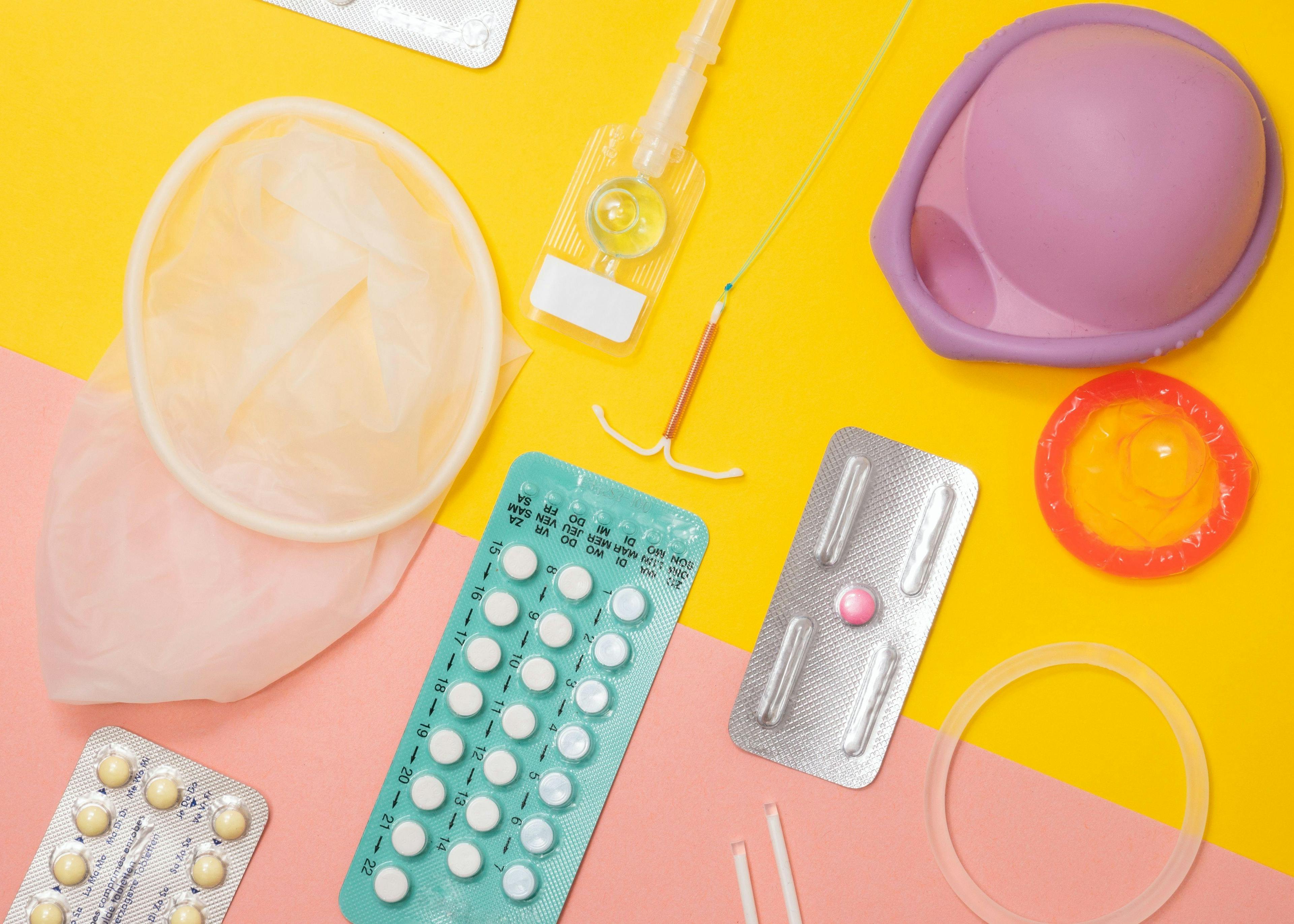 Various types of birth control spread out on a yellow and coral background